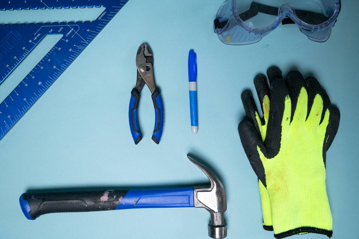 essential tools for basic home repairs: close-up of a compact toolbox containing a tape measure, combination wrench set, magnetic bit holder, utility knife, and needle-nose pliers arranged on a clean workbench